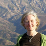 Photo d'une femme regardant l'appareil photo et souriant avec des montagnes en arrière-plan